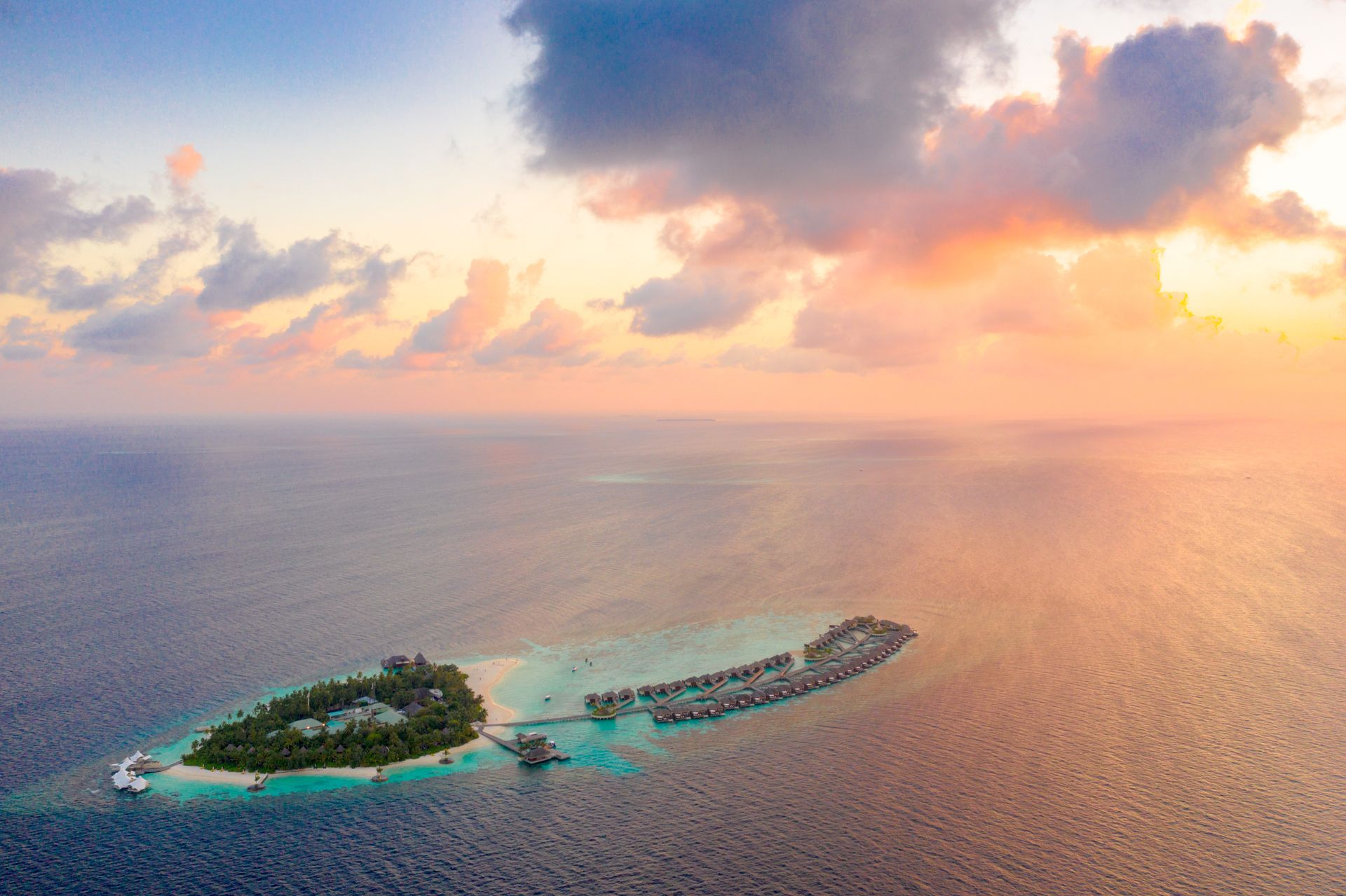 A tropical island and overwater villas at sunset